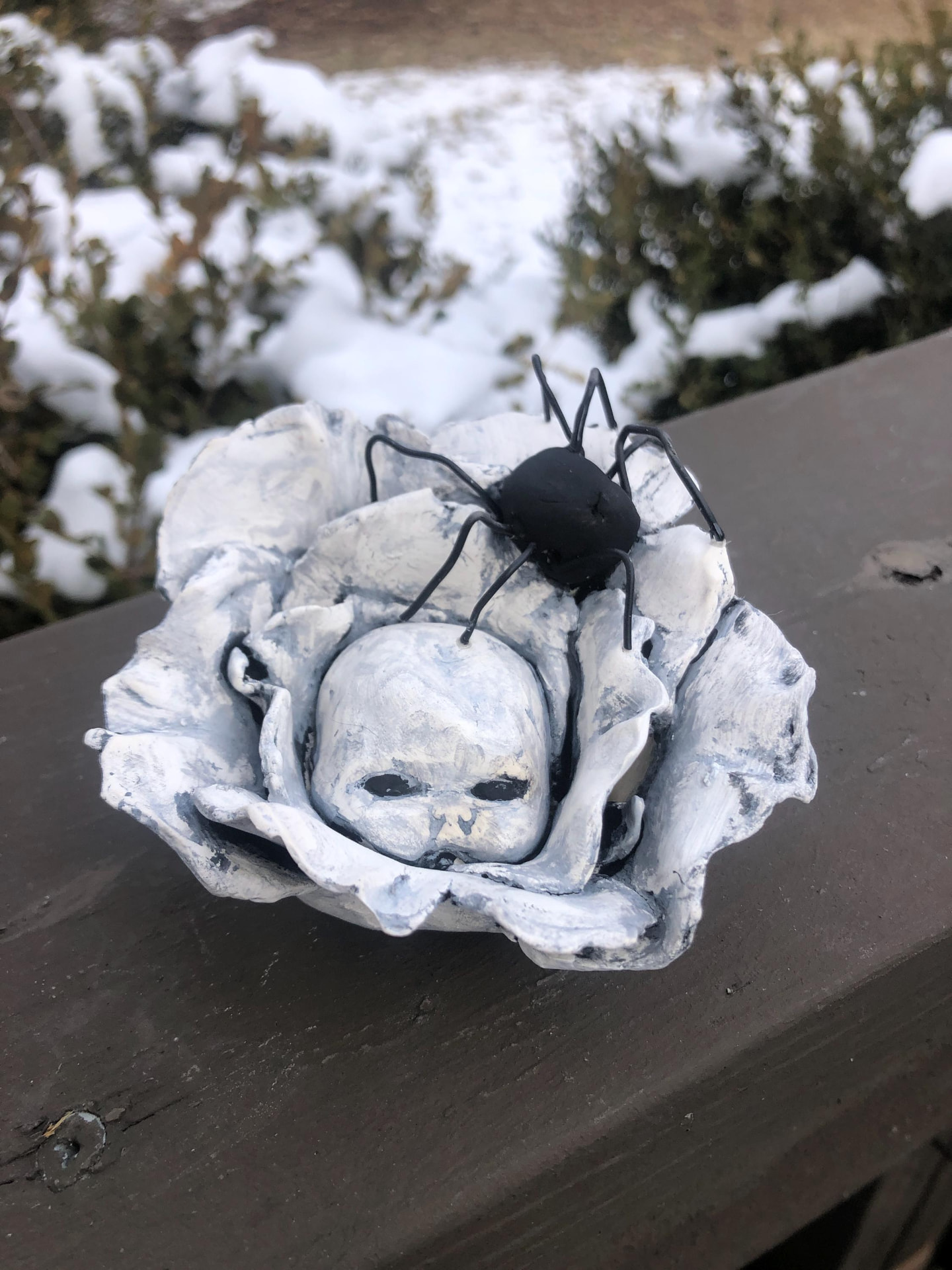 Doll head sculpture nestled in a flower with a black spider